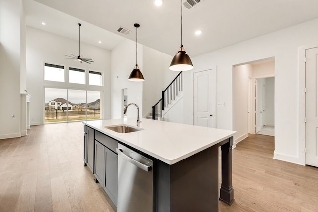 kitchen with stainless steel dishwasher, ceiling fan, sink, light hardwood / wood-style floors, and hanging light fixtures