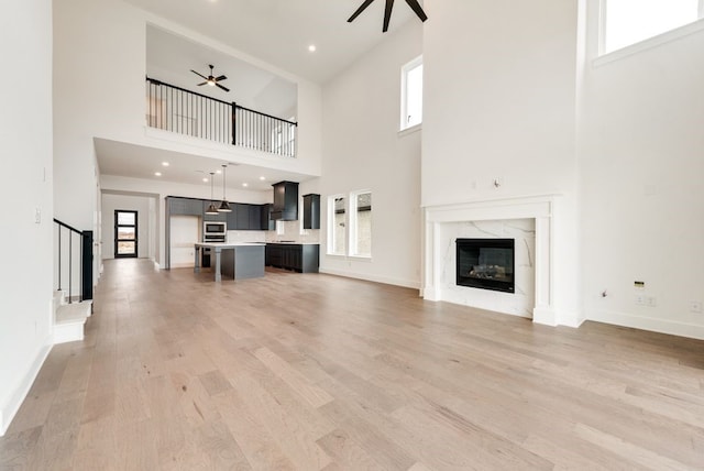 unfurnished living room featuring plenty of natural light, a high ceiling, and light hardwood / wood-style flooring