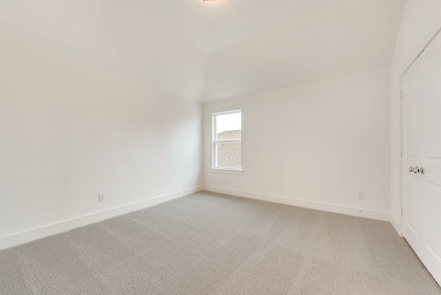 unfurnished room featuring lofted ceiling and light carpet