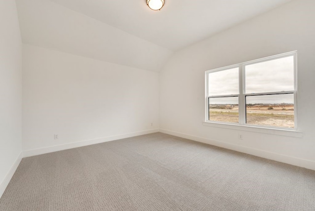 carpeted empty room featuring lofted ceiling