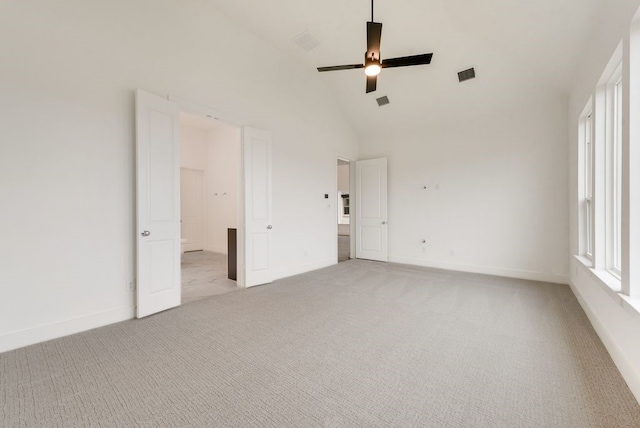 carpeted empty room with ceiling fan and high vaulted ceiling