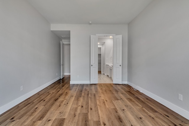 unfurnished bedroom featuring light hardwood / wood-style flooring and connected bathroom