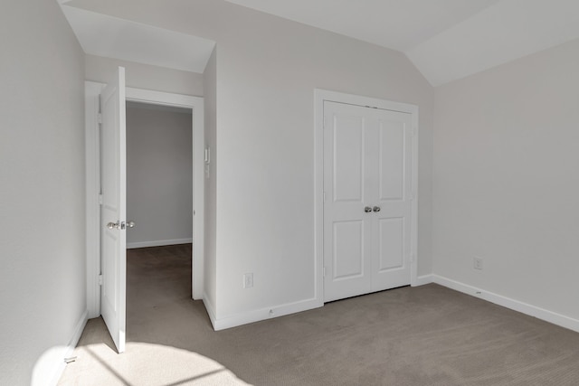 unfurnished bedroom featuring light colored carpet, a closet, and vaulted ceiling