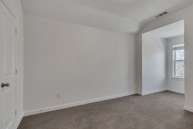 carpeted empty room featuring vaulted ceiling