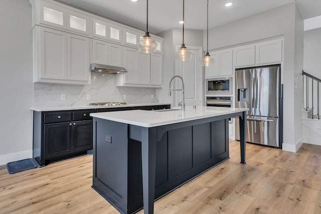 kitchen with ventilation hood, white cabinetry, a center island with sink, and appliances with stainless steel finishes