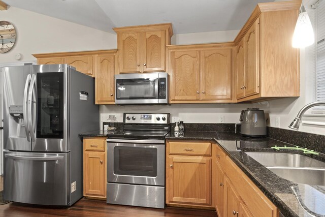 kitchen with sink, appliances with stainless steel finishes, dark hardwood / wood-style floors, dark stone countertops, and lofted ceiling