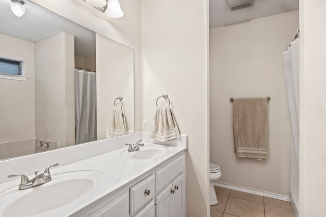 bathroom with toilet, vanity, and tile patterned floors