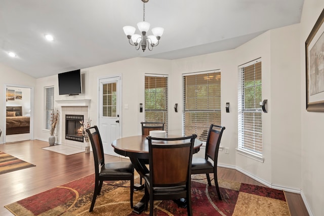 dining room featuring plenty of natural light, a tile fireplace, an inviting chandelier, and dark hardwood / wood-style flooring