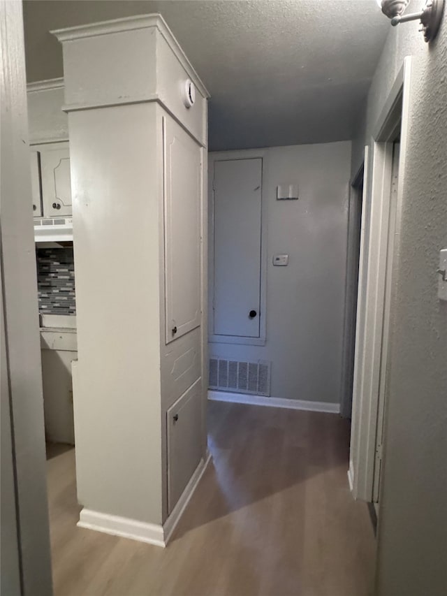 hallway featuring wood-type flooring and a textured ceiling