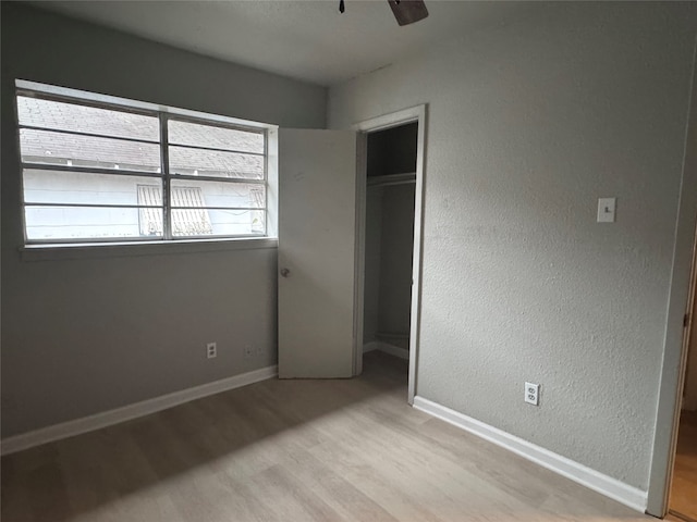 unfurnished bedroom with ceiling fan, a closet, and light wood-type flooring