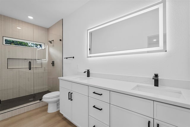 bathroom featuring hardwood / wood-style floors, vanity, toilet, and a shower with shower door