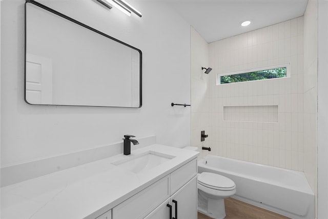 full bathroom featuring toilet, tiled shower / bath combo, vanity, and hardwood / wood-style floors