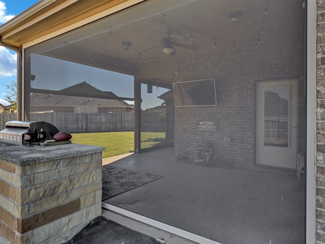 view of patio featuring ceiling fan, a bar, grilling area, and exterior kitchen