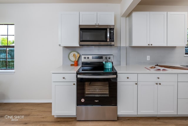 kitchen with light wood-type flooring, appliances with stainless steel finishes, decorative backsplash, and white cabinets