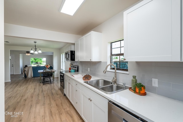 kitchen with white cabinets, light hardwood / wood-style flooring, sink, backsplash, and appliances with stainless steel finishes