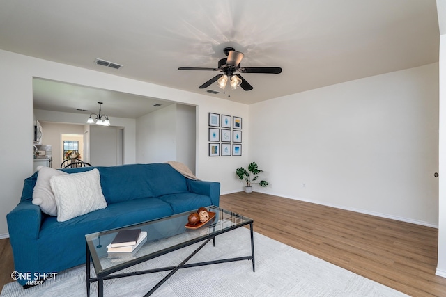 living room with ceiling fan with notable chandelier and wood-type flooring