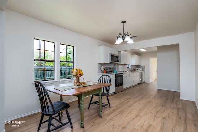 dining space featuring a chandelier, sink, and light hardwood / wood-style flooring