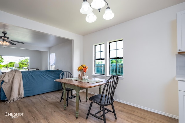 dining space with ceiling fan with notable chandelier and light hardwood / wood-style floors