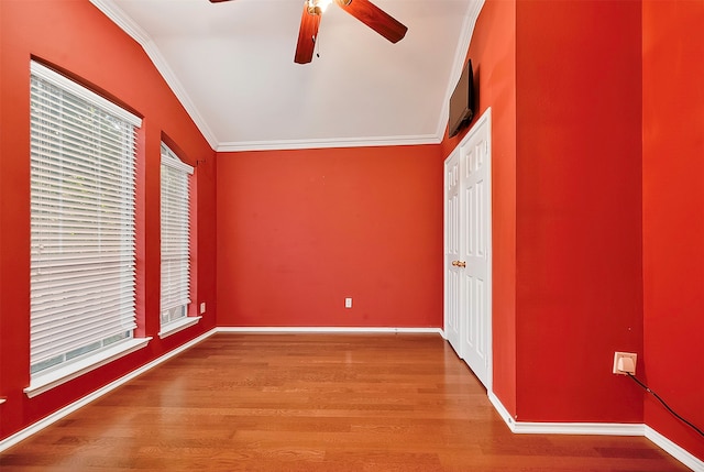 interior space with multiple windows, wood-type flooring, ceiling fan, and crown molding