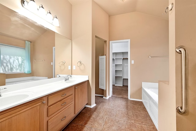 bathroom with vanity, vaulted ceiling, tile patterned flooring, and a tub