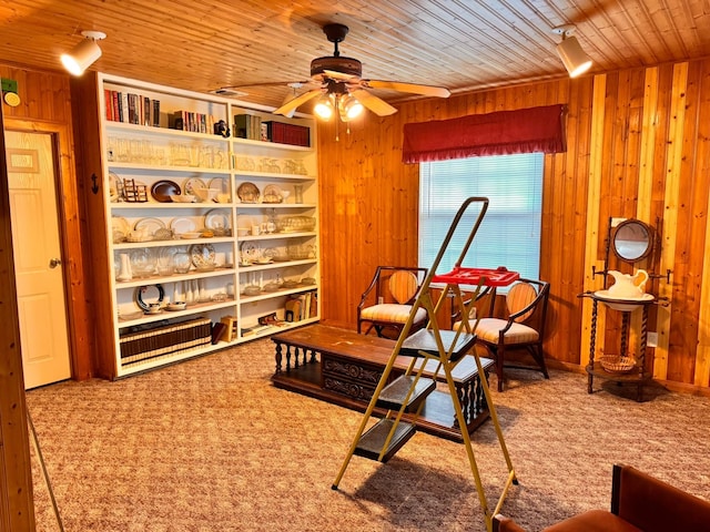 living area with wood ceiling, ceiling fan, wooden walls, and carpet