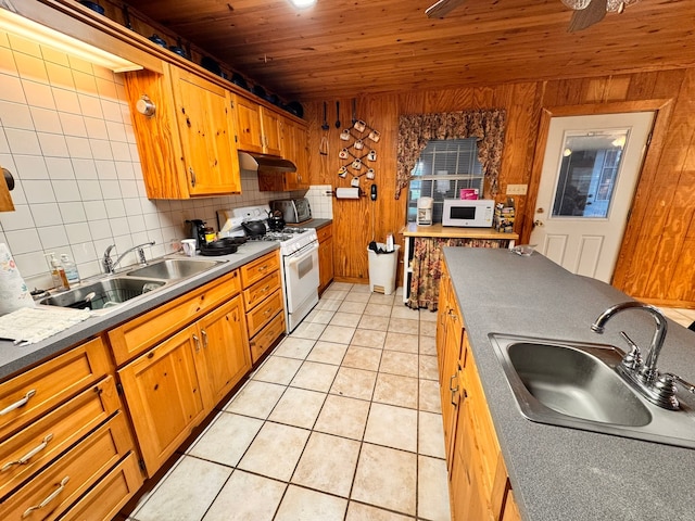 kitchen with decorative backsplash, wood walls, sink, and white appliances