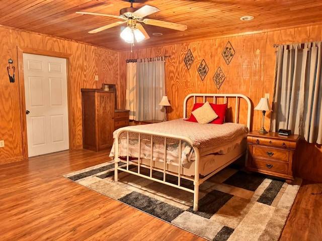 bedroom with wood ceiling, wood-type flooring, ceiling fan, and wood walls