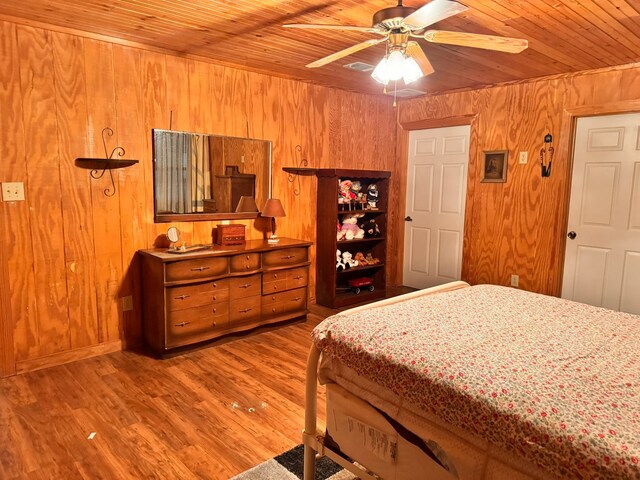 bedroom featuring wood ceiling, wood-type flooring, ceiling fan, and wood walls