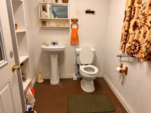 bathroom featuring sink, concrete flooring, and toilet