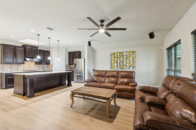 living room featuring ceiling fan, sink, and light hardwood / wood-style floors