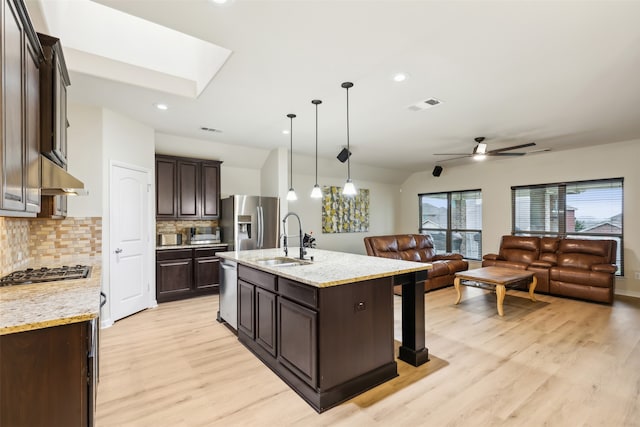 kitchen with hanging light fixtures, sink, an island with sink, light wood-type flooring, and appliances with stainless steel finishes