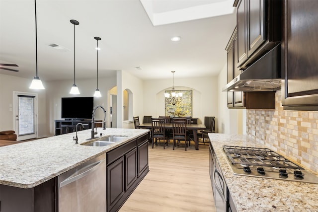 kitchen featuring a center island with sink, decorative backsplash, sink, light wood-type flooring, and appliances with stainless steel finishes