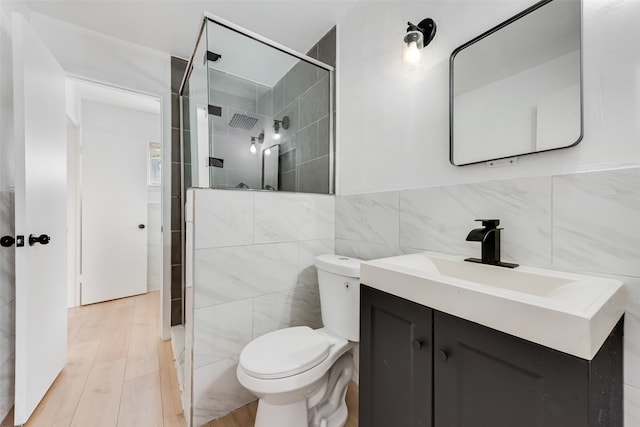 bathroom with toilet, walk in shower, tile walls, and vanity