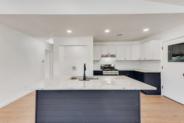 kitchen featuring under cabinet range hood, a sink, visible vents, white cabinetry, and gas stove