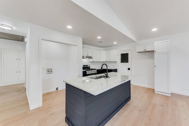 kitchen with backsplash, gas stove, white cabinetry, a sink, and under cabinet range hood