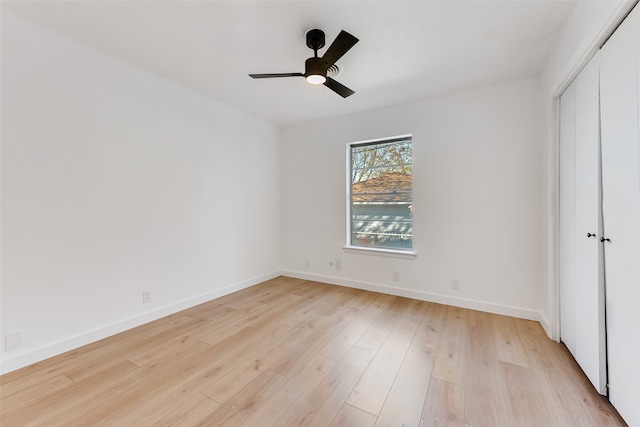 unfurnished bedroom featuring a ceiling fan, a closet, light wood-style flooring, and baseboards