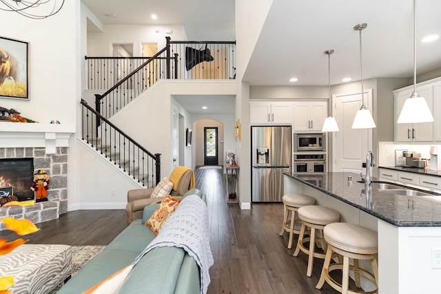 living room featuring sink, a fireplace, dark hardwood / wood-style flooring, and a towering ceiling