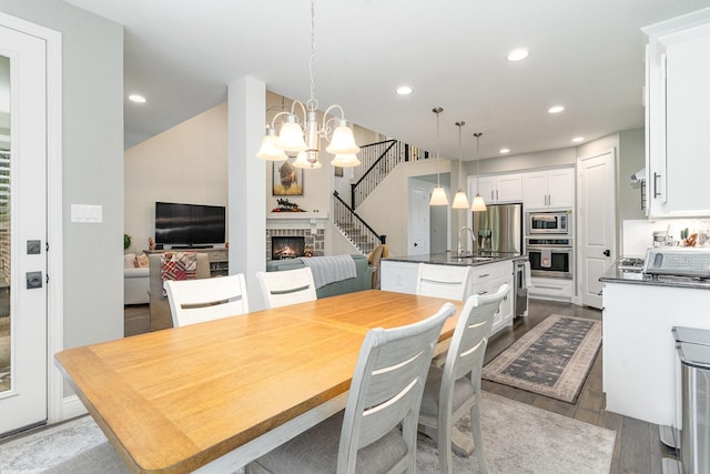 dining room with a notable chandelier, a fireplace, light hardwood / wood-style floors, and sink