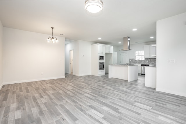 kitchen with white cabinets, stainless steel appliances, wall chimney exhaust hood, and light hardwood / wood-style floors