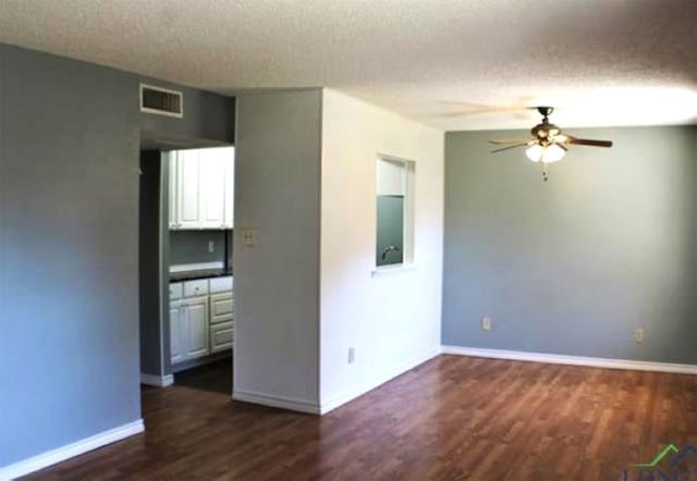 empty room featuring ceiling fan, dark hardwood / wood-style floors, and a textured ceiling