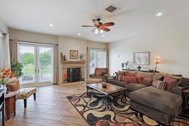 living room featuring ceiling fan with notable chandelier, light hardwood / wood-style flooring, and a healthy amount of sunlight