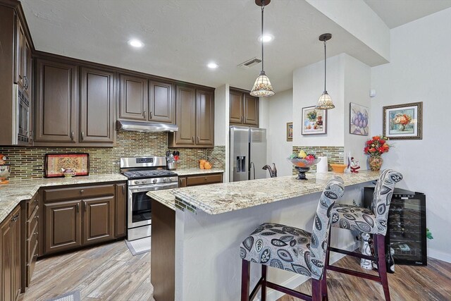 kitchen featuring sink, appliances with stainless steel finishes, tasteful backsplash, light hardwood / wood-style flooring, and pendant lighting