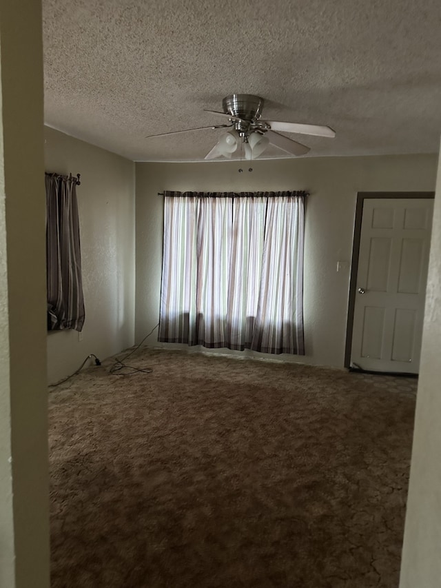 carpeted empty room with ceiling fan and a textured ceiling