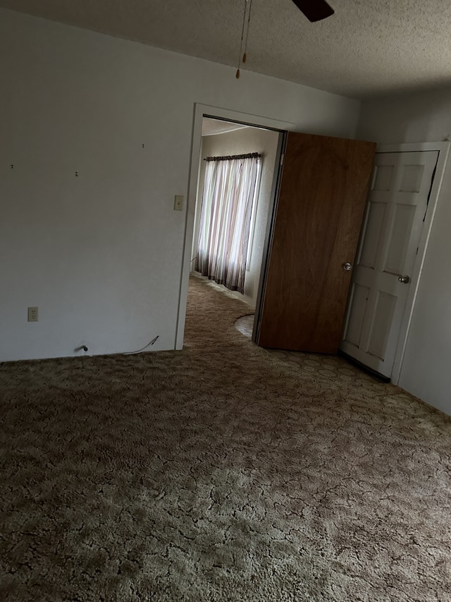 carpeted empty room with ceiling fan and a textured ceiling