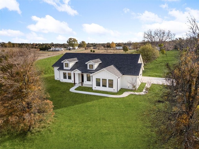 view of front of house with a rural view and a front lawn