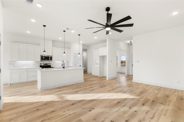 kitchen with a kitchen island with sink, white cabinetry, light hardwood / wood-style floors, and appliances with stainless steel finishes