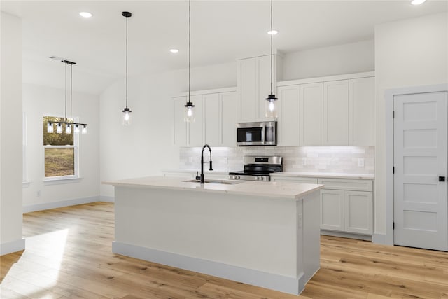 kitchen featuring white cabinetry, a center island with sink, stainless steel appliances, and light wood-type flooring