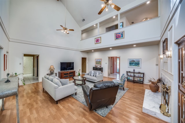 living room with ceiling fan, light hardwood / wood-style flooring, and high vaulted ceiling