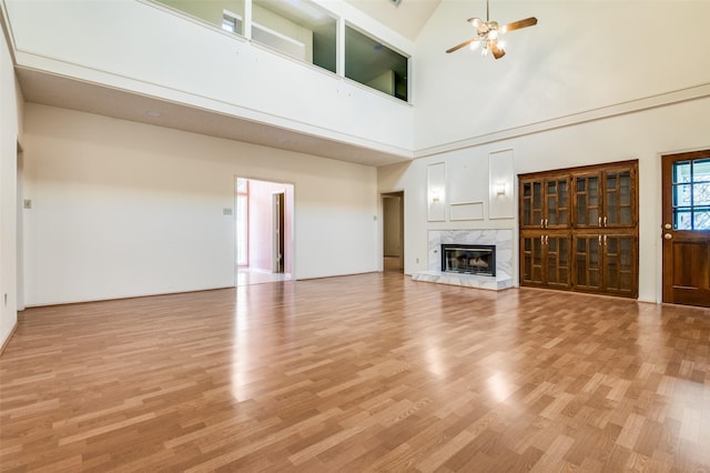 unfurnished living room with light wood-style flooring, a ceiling fan, and a premium fireplace