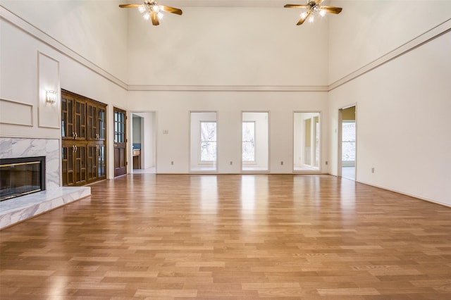 unfurnished living room with a fireplace, light wood-style floors, and ceiling fan